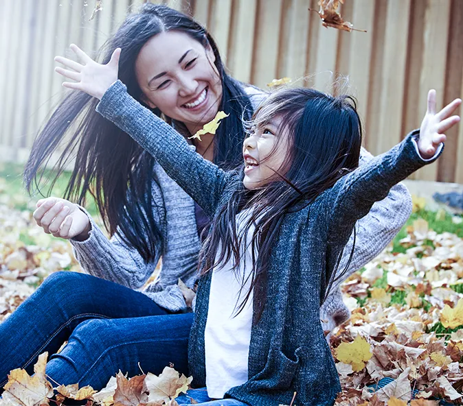 Healthy Life - Mother and daughter leaf throwing in garden